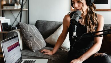 woman in black tank top sitting on couch using macbook